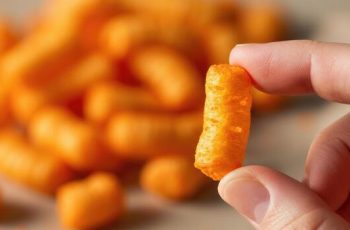 close-up-of-hand-holding-cheese-puff-snack-with-more-in-background-free-photo